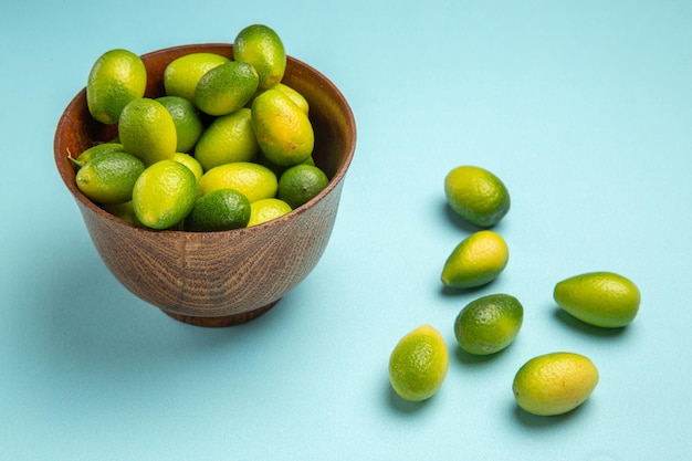 Side close-up view fruits brown bowl of green fruits on the blue surface