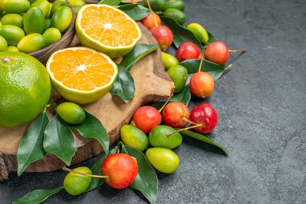 Side close-up view fruits cherries citrus fruits with leaves on the wooden board