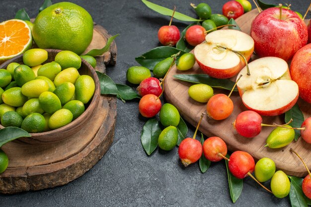 Side close-up view fruits citrus fruits in bowl red apples cherries on the board