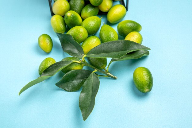 Side close-up view fruits green-yellow fruits with leaves in the grey basket on the blue table