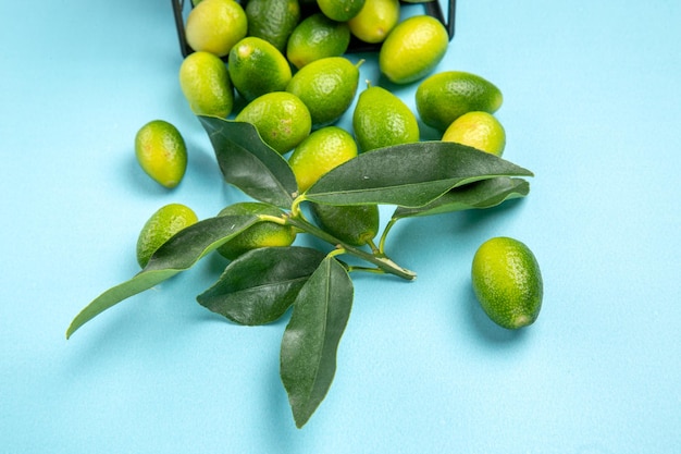 側面のクローズアップビュー果物緑黄色の果物と青いテーブルの灰色のバスケットの葉