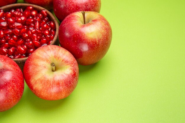 측면 클로즈업 보기 과일 빨간 사과 그릇에 식욕을 돋우는 석류 씨앗이 테이블에 있습니다.