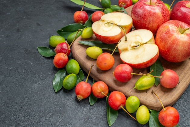 Вид сбоку крупным планом фрукты красные яблоки вишня цитрусовые на доске