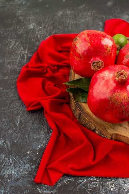 Free photo side close-up view fruits ripe pomegranates on the wooden board on the red tablecloth