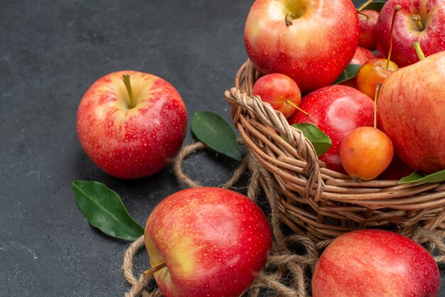 Side close-up view fruits rope cherries and apples in the basket