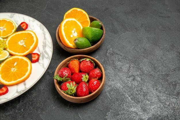 오른쪽 테이블에 있는 얇게 썬 오렌지 레몬과 초콜릿으로 덮인 딸기 접시 옆에 있는 감귤류 과일과 딸기의 테이블 접시에 있는 측면 클로즈업 보기 과일