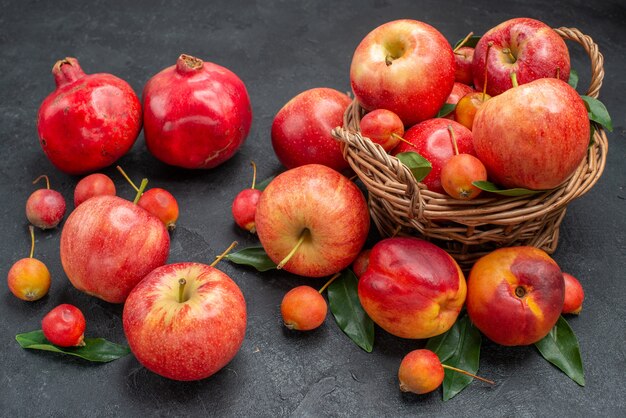 Side close-up view fruits the wooden basket of apples cherries leaves nectarine pomegranates