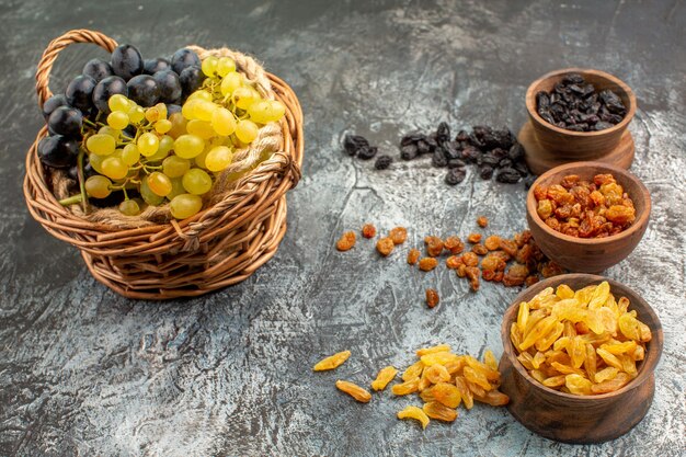 Side close-up view grapes bowls of dried fruits the appetizing grapes in the basket