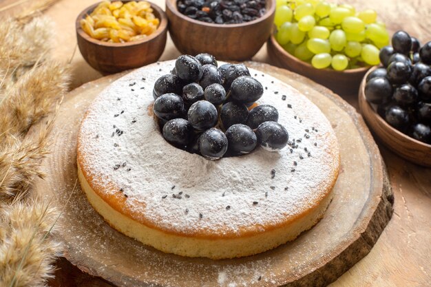 Side close-up view grapes a cake with grapes bowls of raisins grapes spikelets