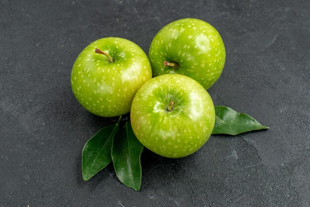 Side close-up view green apples the appetizing green apples with leaves on the dark table