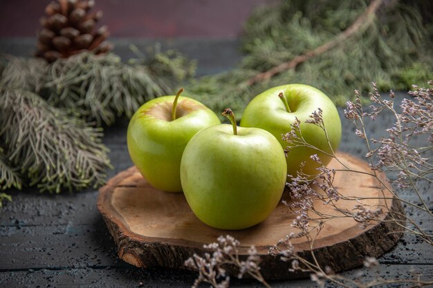 Side close-up view green apples appetizing three apples on wooden board next to spruce branches with cones