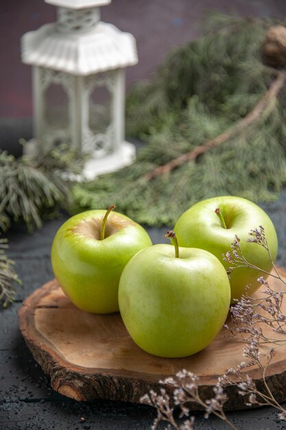 Side close-up view green apples appetizing three green apples on wooden board next to tree branches