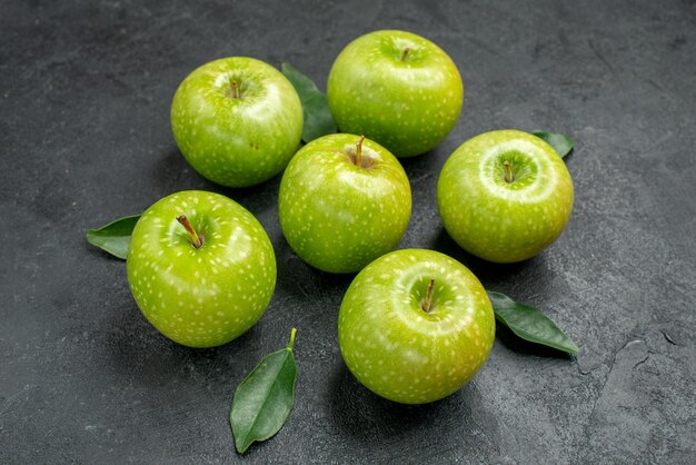 측면 클로즈업 보기 녹색 사과 어두운 탁자에 잎이 있는 식욕을 돋우는 6개의 녹색 사과
