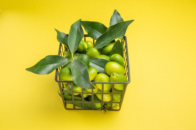 측면 클로즈업 보기 녹색 과일 회색 바구니에 잎이 있는 식욕을 돋우는 녹색 과일