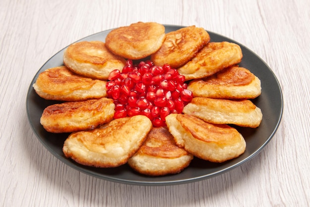 Side close-up view pancakes appetizing pancakes and seeds of pomegranate on the white table