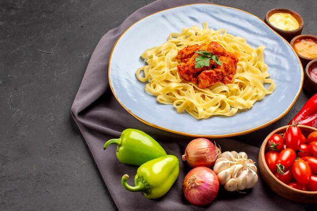 식탁에 있는 보라색 식탁보에 고기와 그레이비 토마토 소스 마늘 양파 볼 후추를 곁들인 식욕을 돋우는 파스타의 테이블 접시에 있는 측면 클로즈업 보기 파스타