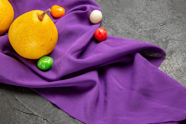 Side close-up view pears and candies colorful sweets and pears on the purple tablecloth on the table