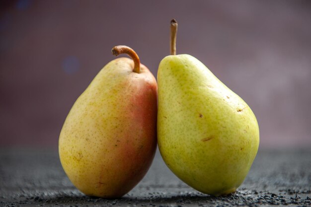 Side close-up view pears on table two ripe green-yellow-red pears on the wooden table