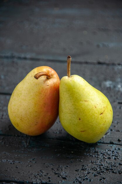 Side close-up view pears on table two ripe green-yellow-red pears on the wooden table