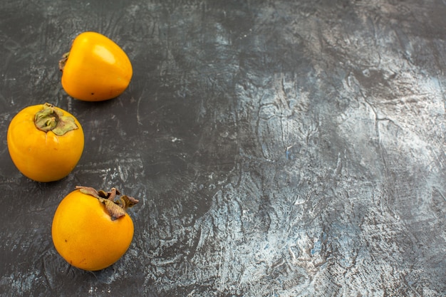 Side close-up view persimmons the appetizing persimmons on the grey background