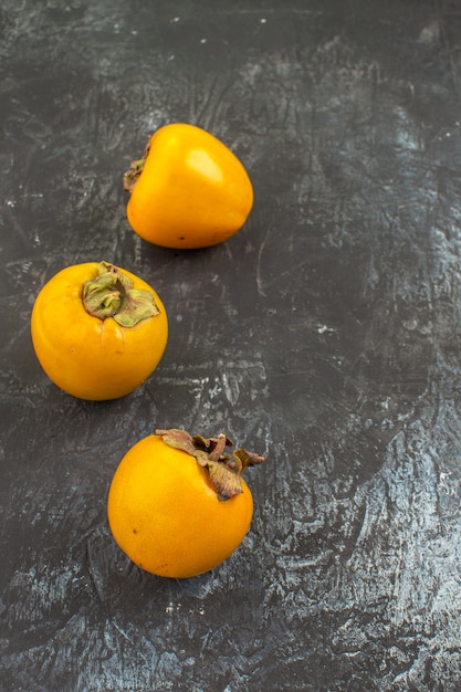 Side close-up view persimmons three appetizing persimmons on the grey table