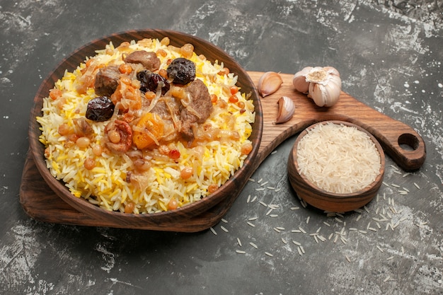 Side close-up view pilaf garlic bowl of rice an appetizing pilaf on the wooden kitchen board