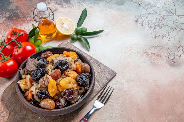 Free photo side close-up view pilaf the wooden board with pilaf fork tomatoes lemon bottle of oil