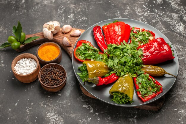 Side close-up view plate of peppers plate of peppers with herbs garlic on the cutting board spices