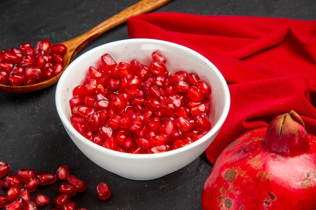 Side close-up view pomegranate bowl of seeds of pomegranate spoon pomegranate tablecloth