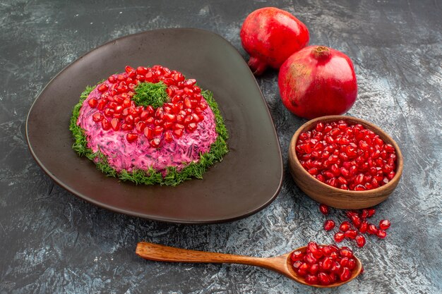 Side close-up view pomegranates an appetizing dish bowl of pomegranate seeds spoon