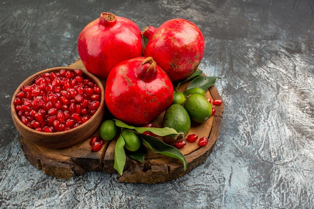 Side close-up view pomegranates appetizing red pomegranate with leaves on the wooden cutting board