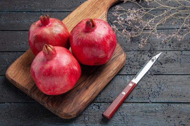 Side close up view pomegranates on board ripe pomegranates on cutting board next to knife and tree branches