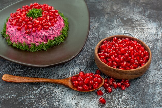 Side close-up view pomegranates dish of pomegranate herbs pomegranate seeds in the bowl spoon