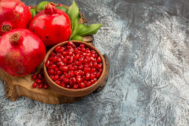 Вид сбоку крупным планом гранаты вкусный гранат с зелеными листьями на разделочной доске