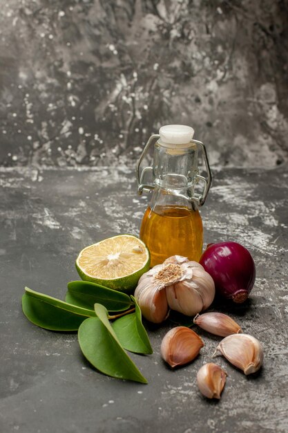 Side close-up view spices onion lemon leaves garlic and bottle of oil on the table