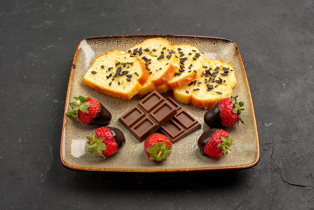 측면 클로즈업 보기 딸기와 케이크 식욕을 돋우는 초콜릿으로 덮인 딸기와 사각형 접시에 초콜릿이 있는 케이크