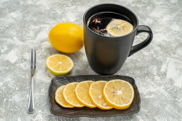 Side close-up view sweets black cup of tea with star anise lemon fork