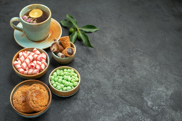 Side close-up view sweets a cup of tea with lemon citrus fruits cookies waffles candies