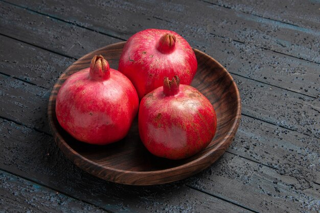 Side close-up view three pomegranates brown bowl of pomegranates on the table