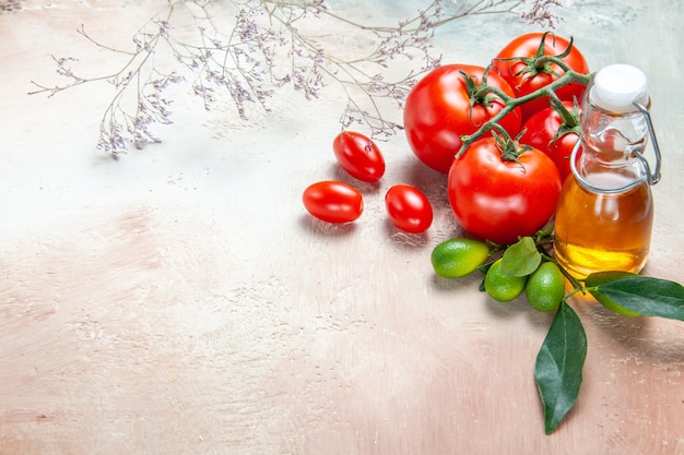 Вид сбоку крупным планом помидоры бутылка масла цитрусовые с листьями помидоры с цветоножками