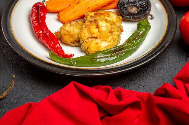 Бесплатное фото Вид сбоку крупным планом овощи тарелка жареных овощей красная скатерть