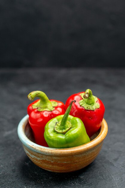 Side close view of bowl of bell peppers on the left side on dark grey table with dark green background