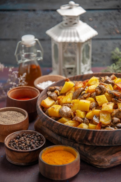 Side close view bowl with food plate with fried mushrooms and potatoes on the board and colorful spices and oil