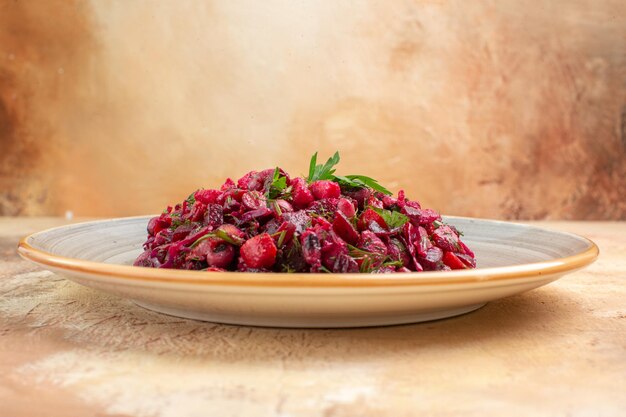 Side close view of plate of a red salad in the center with greens on it on a wooden backgorund