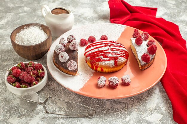 大理石の背景の側面に赤いナプキンの上にベリー粉茶ふるいとチョコレートと甘いプレートの側面拡大図