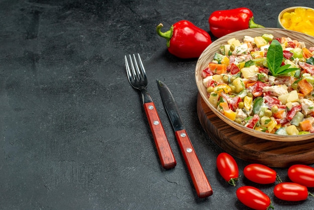 Free photo side close view of veggie salad with vegetables and cutleries on dark grey background