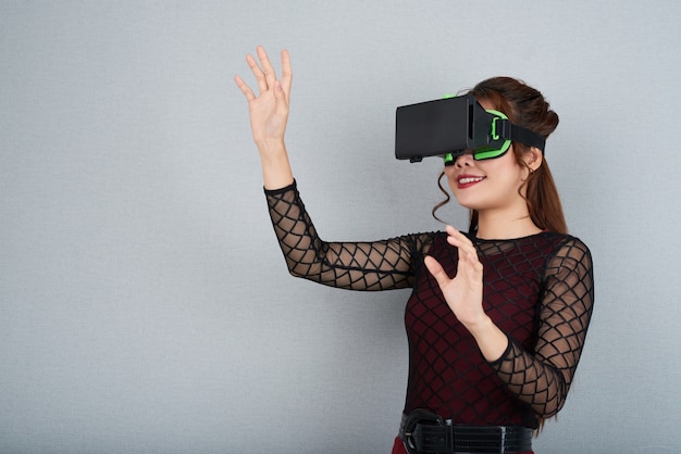 Side cropped view of young woman in VR headset gesturing