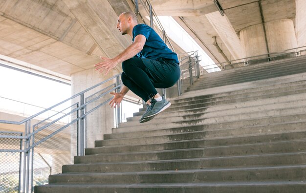 Free photo side view of active young male athlete jumping over staircase