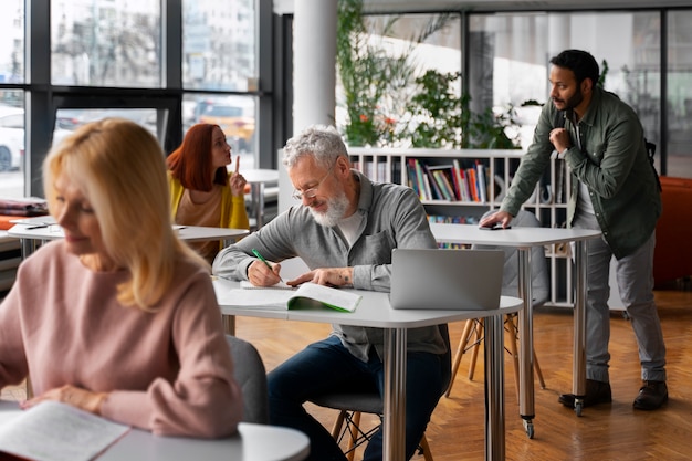 Foto gratuita adulti vista laterale che studiano insieme