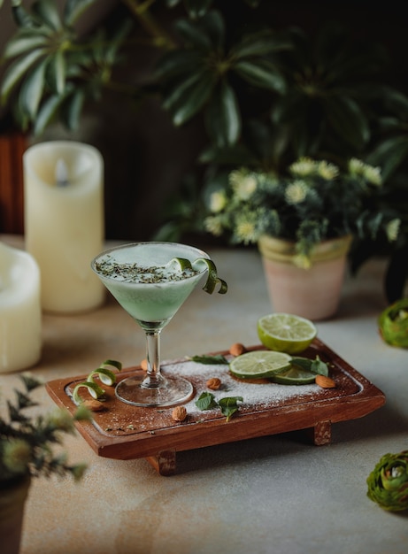 Side view of alcohol cocktail with almond and lime on a wooden board